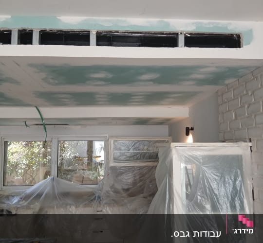 חדר עם תקרת גבס בעבודה, רהיטים מכוסים בניילון